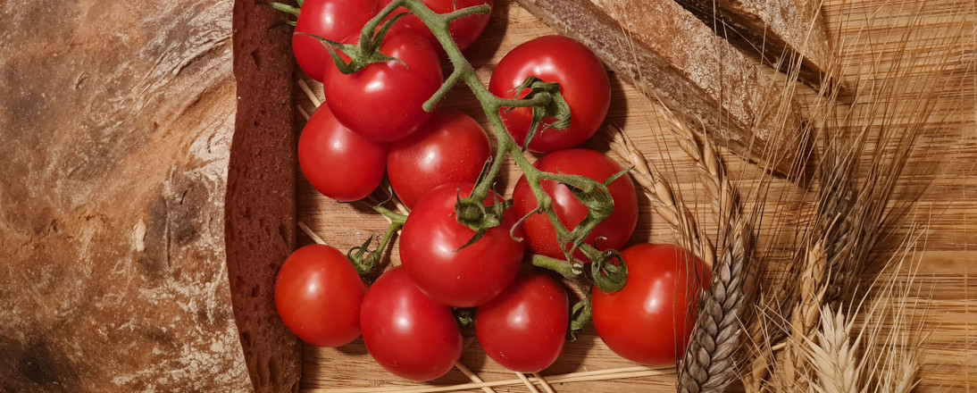 Brot, Tomaten und Getreide liegen auf einem Tisch.